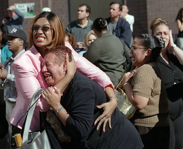 双子塔遭到恐怖袭击后，两名受惊的妇女抱在一起痛哭