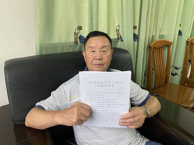 今年80岁的徐国梁手持温州中院的行政判决书。本文图片受访者提供