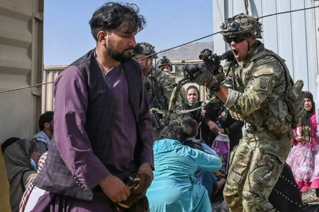 8月16日，在阿富汗喀布尔机场，一名美军士兵用枪指向一名阿富汗男子
