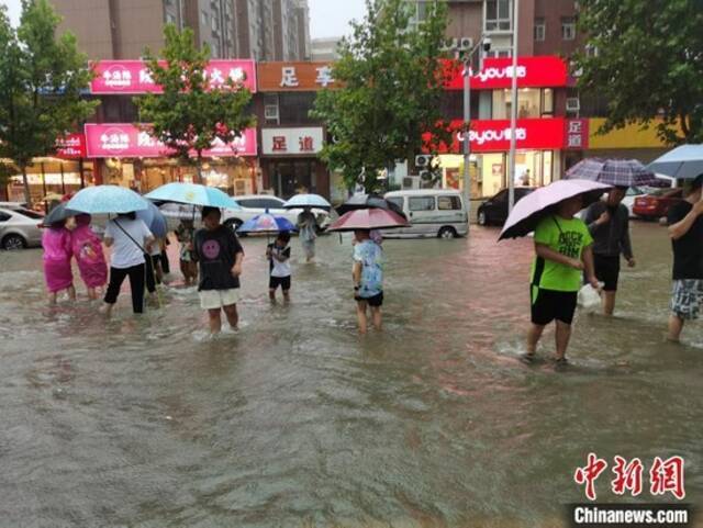 资料图：郑州7·20特大暴雨后，市民在街道上趟水而过。王登峰摄