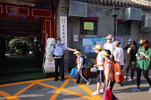  9月1日早上，东城公安分局共投入警力200余人分散在区内各个学校守护校园安全，图为民警在黑芝麻胡同小学引导学生进校。东城公安分局供图