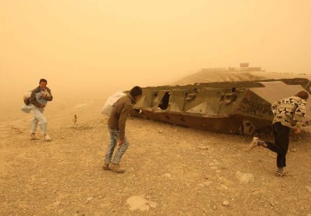 ↑2012年3月19日，几名男孩在喀布尔从沙尘暴中走过。新华社发（马苏德摄）