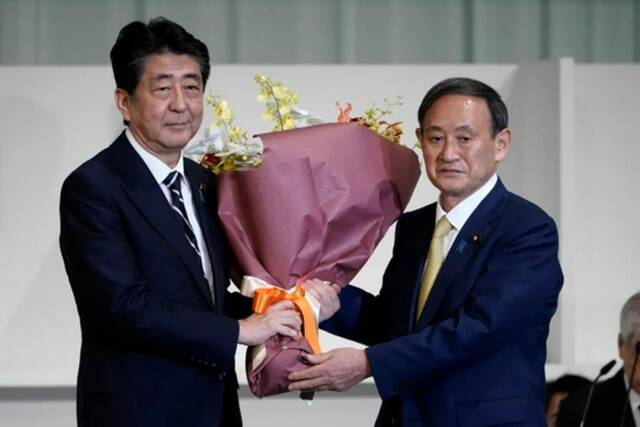 当地时间2020年9月14日，日本东京，菅义伟当选日本自民党总裁，安倍晋三向菅义伟献花祝贺。/IC photo