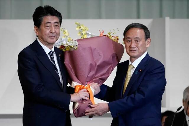 ▲当地时间2020年9月14日，日本东京，菅义伟当选日本自民党总裁，安倍晋三向菅义伟献花祝贺。图/IC photo