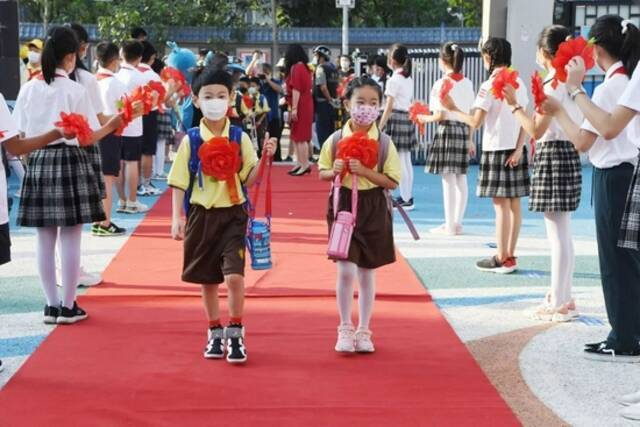 2021年9月1日，北京小学通州分校两名一年级新生戴着大红花走进校园。/视觉中国