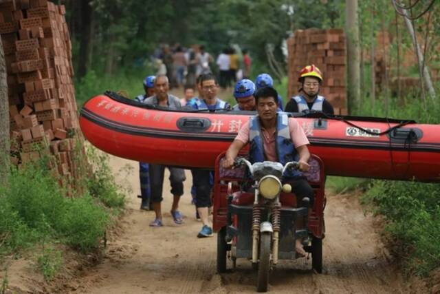 2021年7月22日，受强降雨影响，河南开封尉氏庄头镇多个村庄过水，救援人员用三轮车运输救生艇。