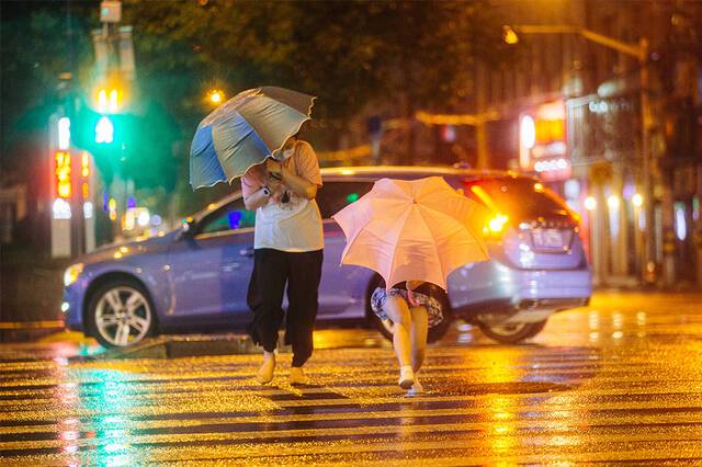 2021年9月13日，上海，河南路宁波路路口，行人躲在伞后过马路。
