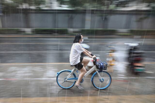 2021年8月，北京突降阵雨，一女士淋雨骑行。新京报记者王嘉宁摄