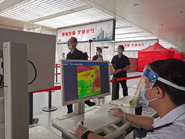 上海站工作人员为进、出站旅客测温。