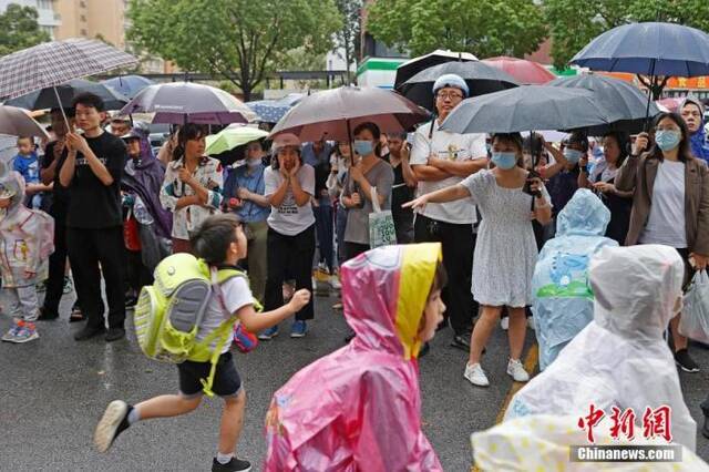 资料图：家长在校外接孩子放学回家。殷立勤摄