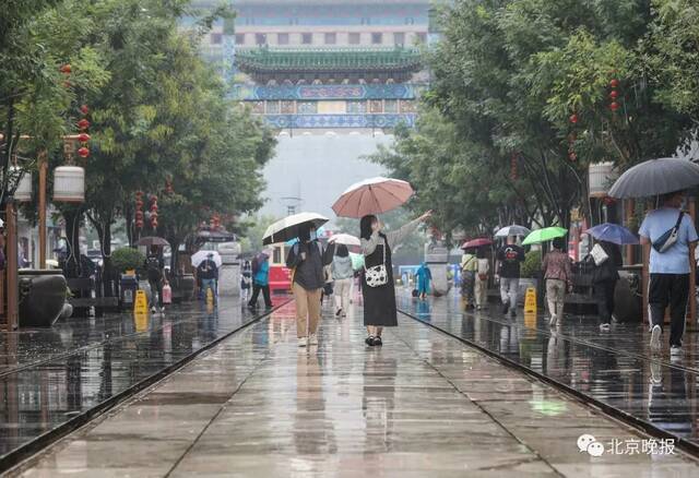 北京迎来降雨天气，游客在前门步行街参观游览。视觉中国供图