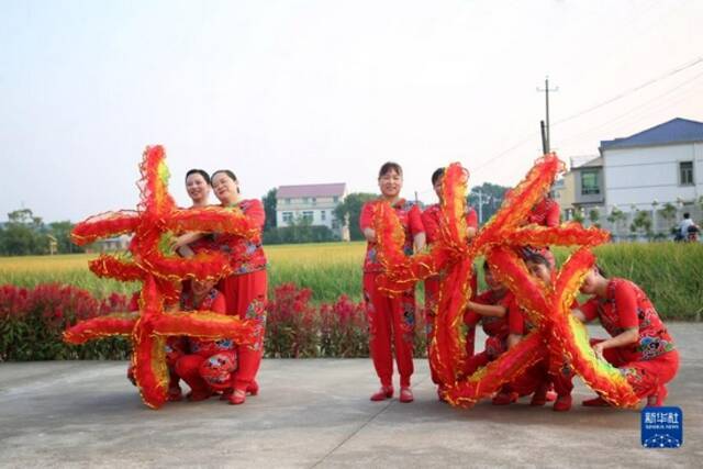 在湖南省汨罗市汨罗镇九雁村稻田旁的小广场上，村里的妇女们在排练以丰收为主题的广场舞（9月17日摄）。新华社发（胡清摄）