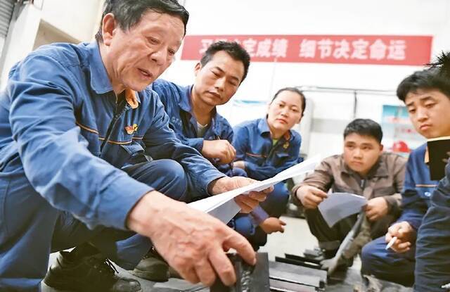 图为2021年6月17日，艾爱国（左一）在湖南湘潭湘钢高级技工学校焊接实习基地检查学生的焊接作业。新华社记者薛宇舸/摄
