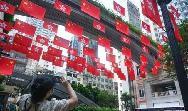 2021年10月1日，香港多区挂满国旗和香港特区区旗，市民纷纷驻足留影