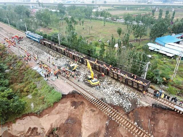 ▲受强降雨影响，南同蒲铁路祁县站至东观站间的昌源河大桥桥台被洪水冲垮。10月7日中午，救援队伍正在从火车上搬运石渣，加固路基，阻拦洪水。