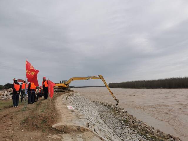 长臂挖掘机正在进行加固河堤的施工作业