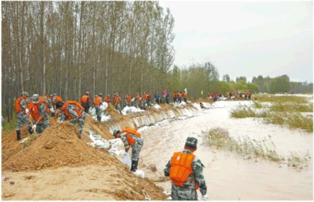 新华社发近日，在东营市东营区，抢险人员在黄河麻湾段加固防汛堤坝。