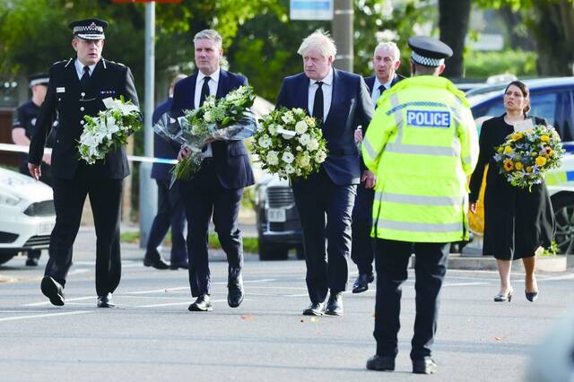 当地时间16日，英国首相约翰逊（中）等人抵达保守党议员阿梅斯遇袭身亡现场，表示哀悼。