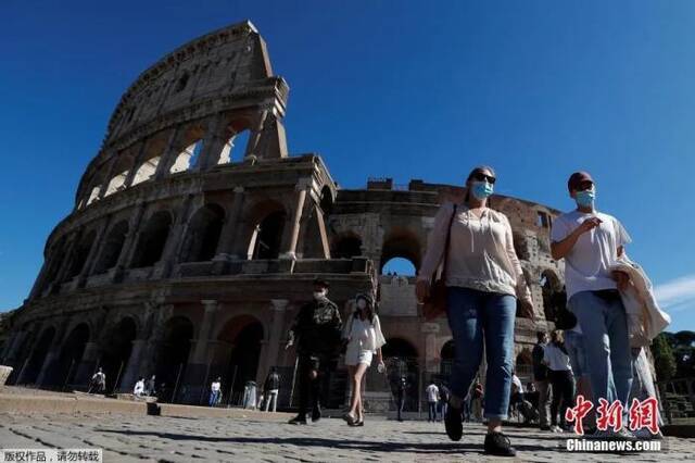 资料图：意大利首都罗马，民众佩戴口罩走过斗兽场。