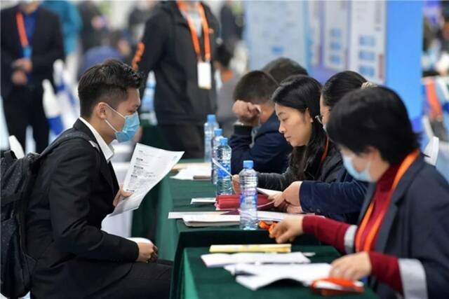 10月23日，在江西省南昌市举行的“百场校招”活动南昌大学主会场，一名毕业生（左）和一家招聘企业的工作人员交谈。新华社记者彭昭之摄