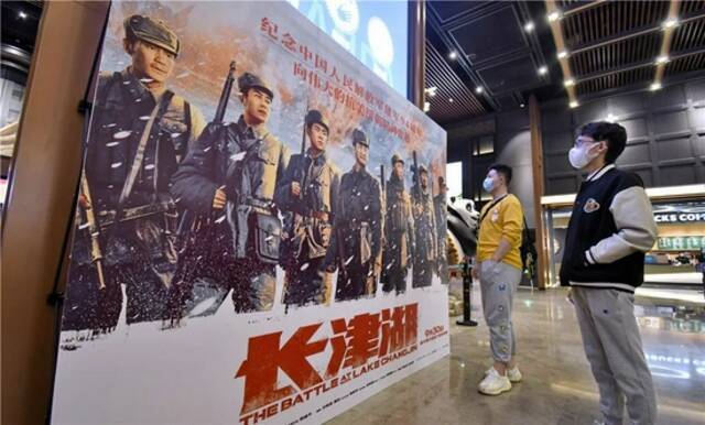  10月7日，两名年轻人在北京一家影院观看电影《长津湖》的海报。新华社记者李欣摄