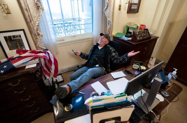 当地时间2021年1月6日，美国华盛顿，特朗普支持者冲进美国国会，闯入美国众议院议长佩洛西办公室，坐在佩洛西的椅子上。图/IC photo