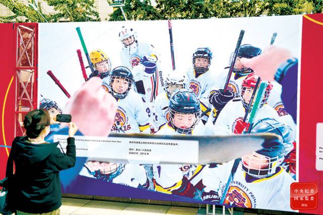 图为观众在北京2022冬奥文化影像专题展上看小学生参加冰雪运动的图片。中央纪委国家监委网站张梓健摄