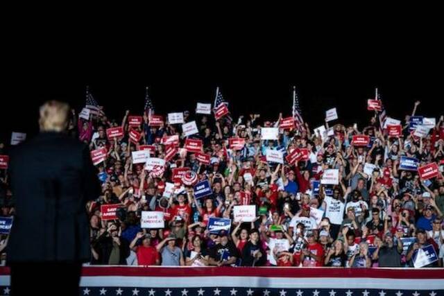 ↑特朗普支持者们在集会中手举“拯救美国”的牌子。