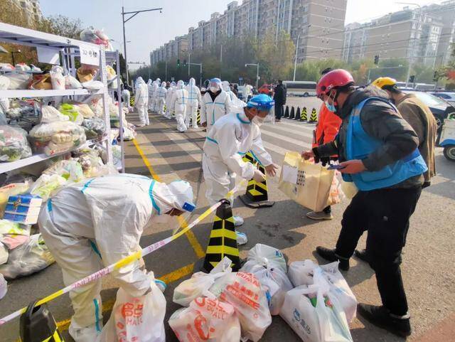 ▲11月3日，北京市昌平区天通苑北二区，外卖小哥将居民订购的生活物品交给防疫人员转送。图/中新图片