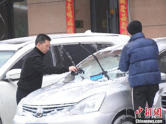 车主在给汽车清理积雪刘栋摄