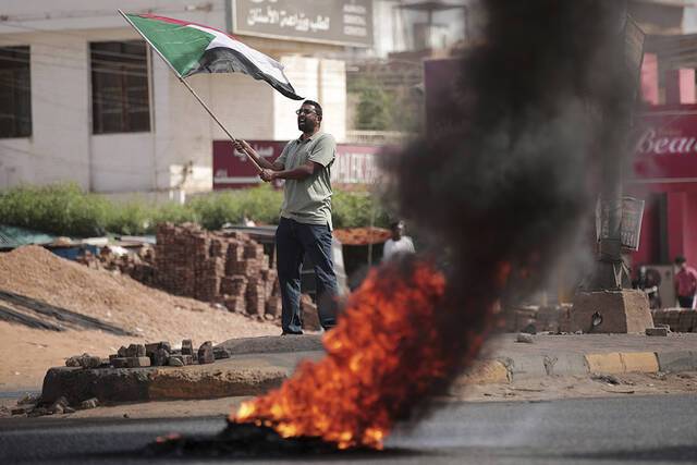 当地时间2021年10月30日，在苏丹喀土穆的一场抗议活动中，一名男子边挥舞苏丹国旗边高呼口号。人民视觉图