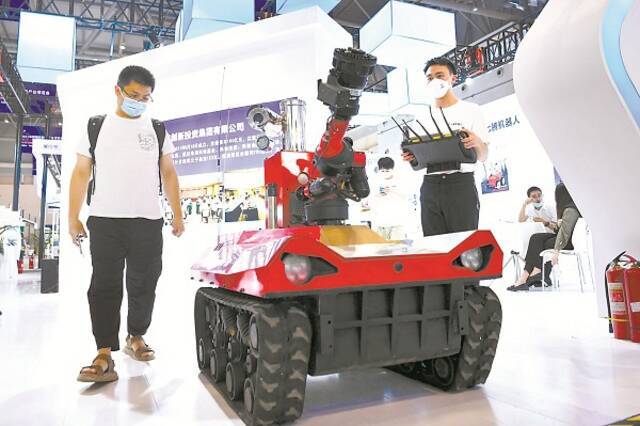 图为今年8月，工作人员（前右）在2021中国国际智能产业博览会现场展示消防灭火侦察机器人。新华社记者唐奕摄