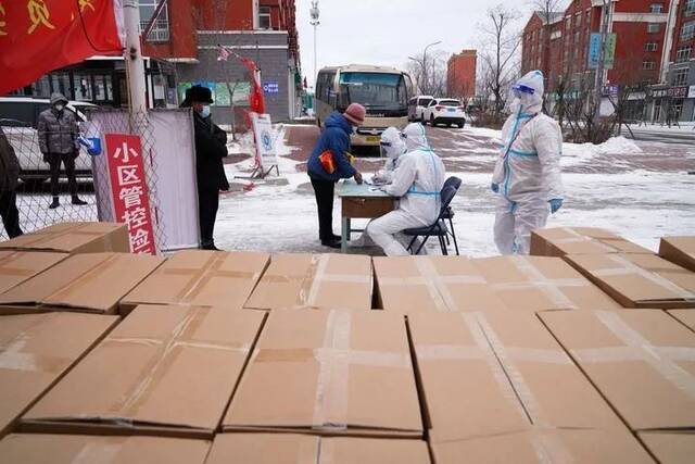 11月10日，在黑龙江省黑河市一小区，社区工作人员为居民发放免费生活物资。新华社记者王松摄