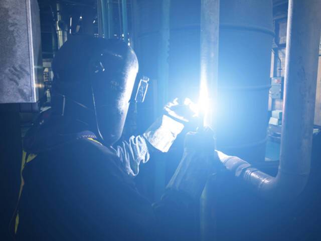 一位戴面罩的工人在用氩弧焊进行焊接。视觉中国供图