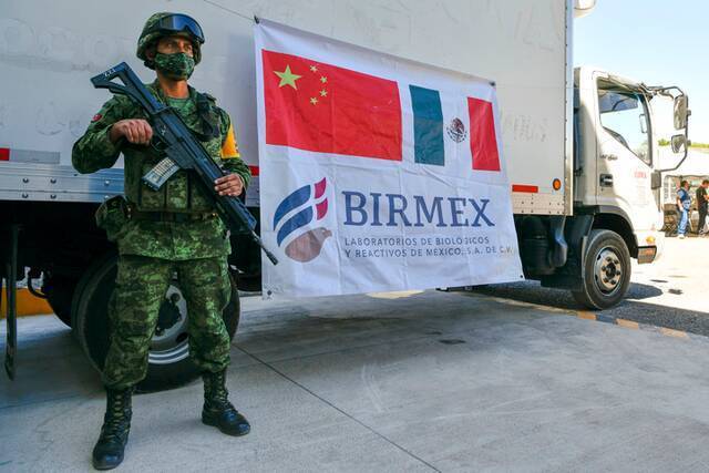 资料图片：3月22日，在墨西哥克雷塔罗市埃尔马克斯产业园，士兵守卫载有康希诺疫苗的运输车。新华社记者辛悦卫摄