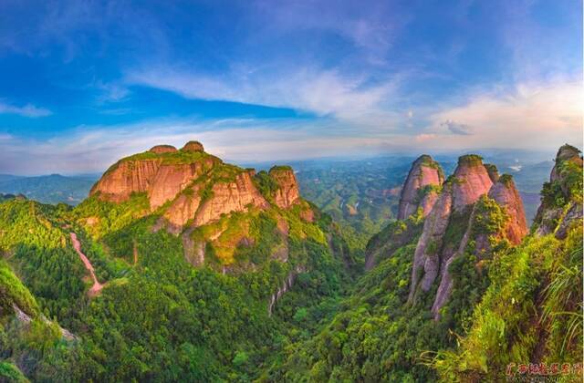 大雪时节，容县大围顶的巍峨山峦在夕阳的映照下流光溢彩，与蓝天、白云共同描绘出一幅静谧的画卷。（玉林市容县纪委监委供图）