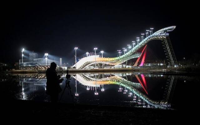 12月12日晚，一位市民在拍摄首钢滑雪大跳台夜景。新京报记者浦峰摄