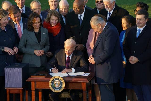 11月15日，美国总统拜登（中）在华盛顿白宫出席基础设施投资法案签字仪式。