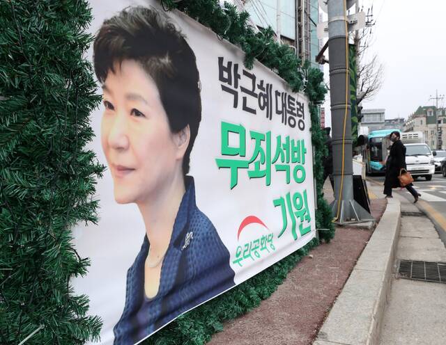 12月24日，韩国江原道春川市市民从一棵祈愿前总统朴槿惠获释的圣诞树旁走过。图丨澎湃影像