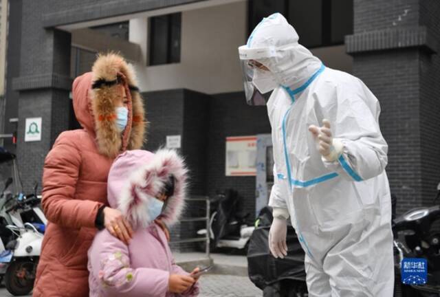 12月27日，在西安市雁塔区孟村小区，卢晨阳（右）向居民介绍核酸检测注意事项。新华社记者张博文摄
