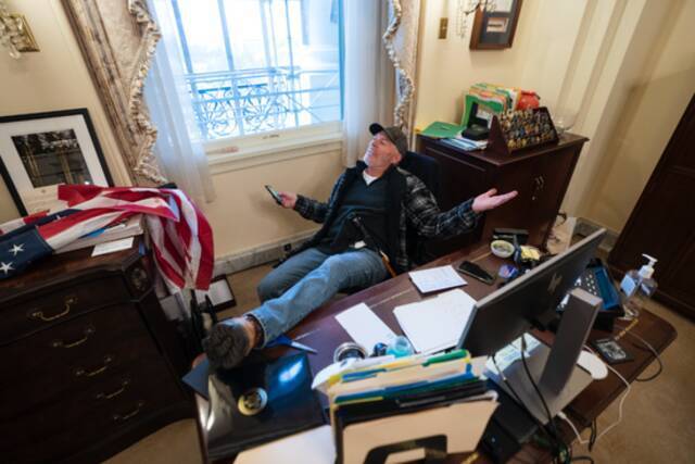 当地时间2021年1月6日，美国华盛顿，特朗普支持者冲进美国国会，闯入美国众议院议长佩洛西办公室，坐在佩洛西的椅子上。/IC photo