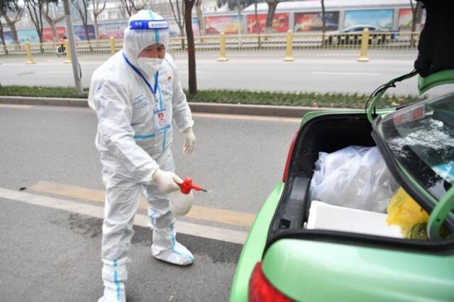 1月5日，西安“的哥”王锋利在出发转运核酸检测样本前为车辆消毒。新华社记者张博文摄