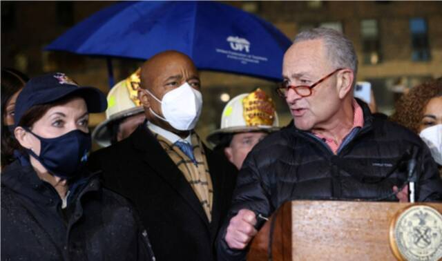 当地时间2022年1月9日，美国纽约市布朗克斯区，纽约州州长凯茜·霍楚尔（左）、纽约市长埃里克·亚当斯（中）以及美国参议院民主党领袖查克·舒默（右）在受灾建筑外讲话。图/IC photo