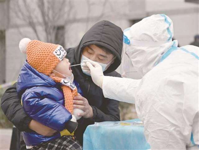 1月9日，在天津市西青区中北镇锦曦花苑社区一处核酸检测点，家长抱着孩子进行核酸检测。新华社记者李然摄