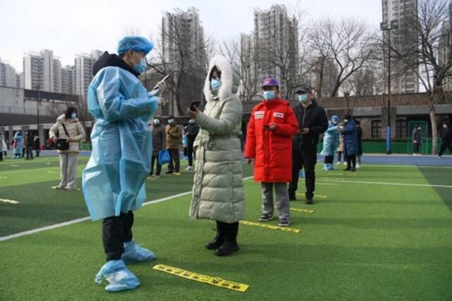 1月9日，在天津市南开区鼓楼街道中营小学核酸检测点，工作人员通过手机扫码为待检测居民录入信息。图片来源：新华社