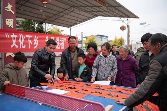 过了腊八就是年，挥毫泼墨写春联。广西壮族自治区鹿寨县组织书法爱好者走进乡村，用写春联、送福字的方式，寄语新春，送福纳祥。（广西壮族自治区鹿寨县纪委监委供覃智锋摄）