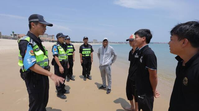 在湄洲岛一处沙滩上，莆田市公安局湄洲派出所景区管理队的工作人员正与游客交流，做安全教育。（莆田市公安局供图）