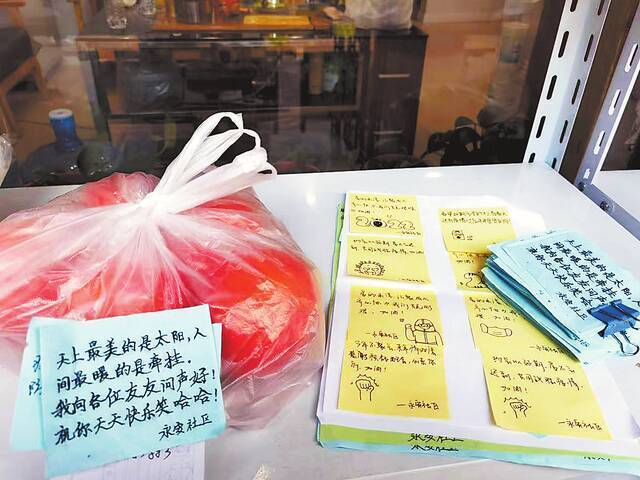 郑州二七区建中街街道永安社区的工作人员,在为居民送去的物资袋上贴上手写的暖心小纸条。（记者供图）