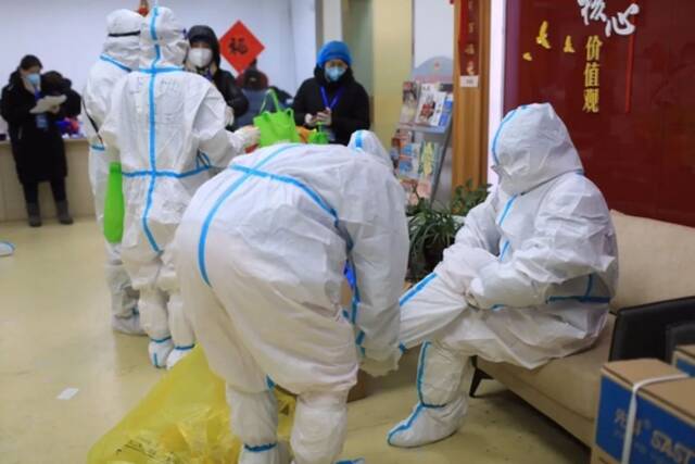 15日，工作人员在穿防护服，准备入户为不方便的居民进行核酸检测。新京报记者浦峰摄