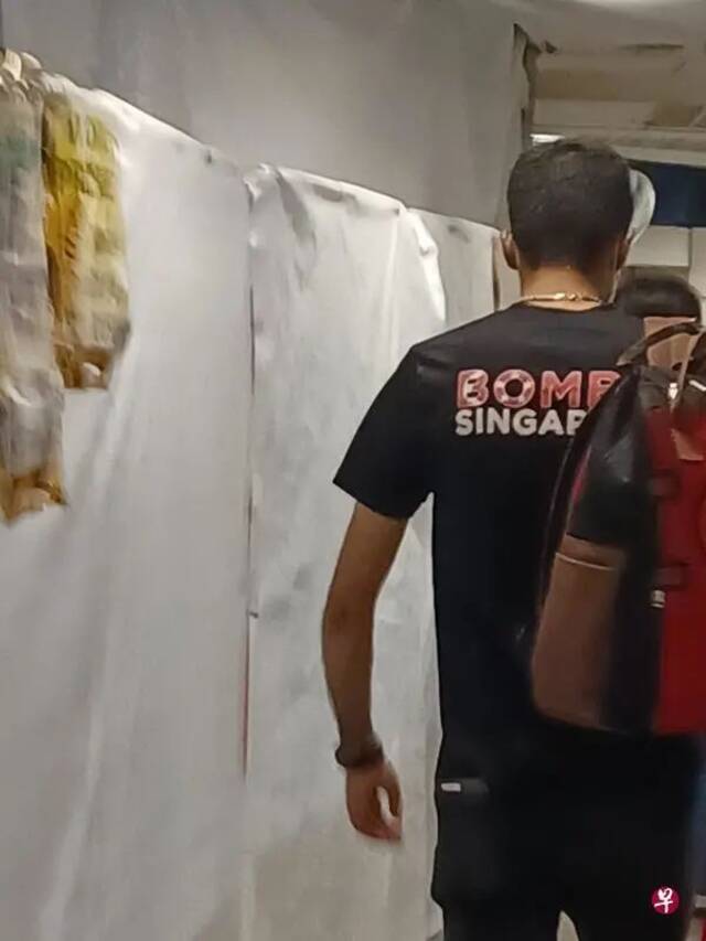 男子穿着一件写有“炸了新加坡”（Bomb Singapore）字眼的衬衫，在地铁站隧道走动。图源：《联合早报》引自受访者
